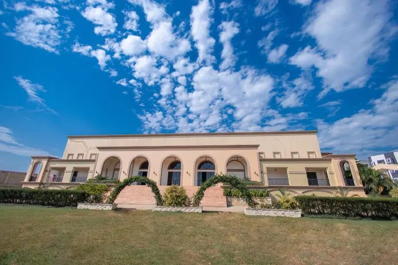 The A&M head office at Nsambya Gardens: a two-storey building with arched windows behind a lawn and hedge arches