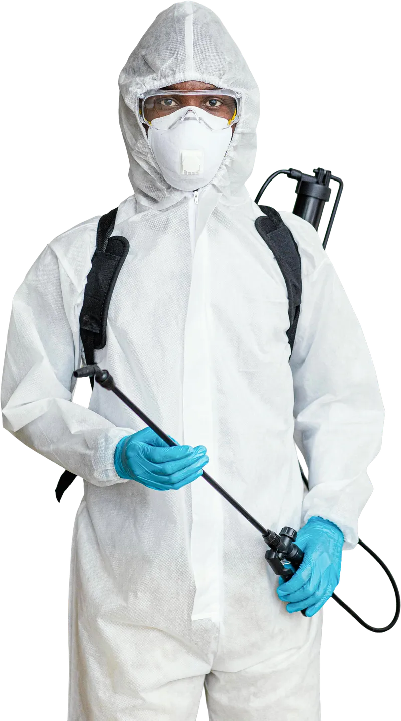 An A&M technician in a white protective suit, mask and goggles, holding a sprayer
