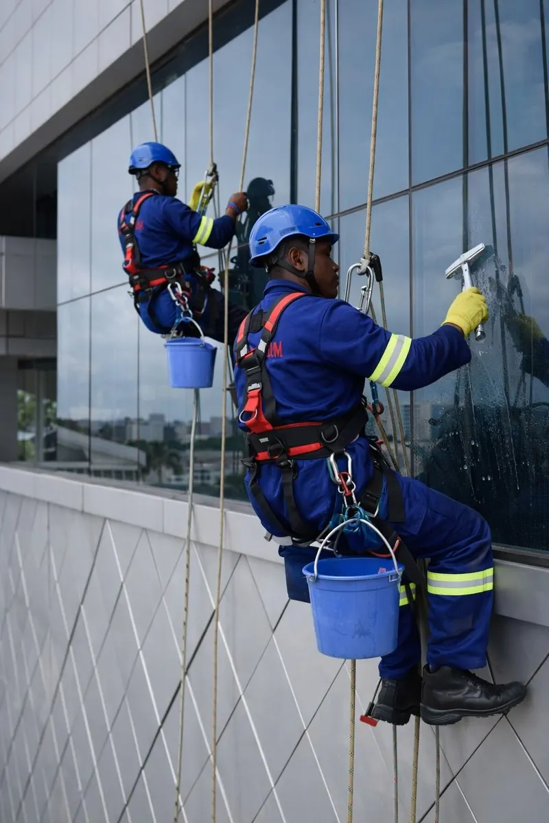 Two A&M technicians on ropes cleaning the glass facade of a building
